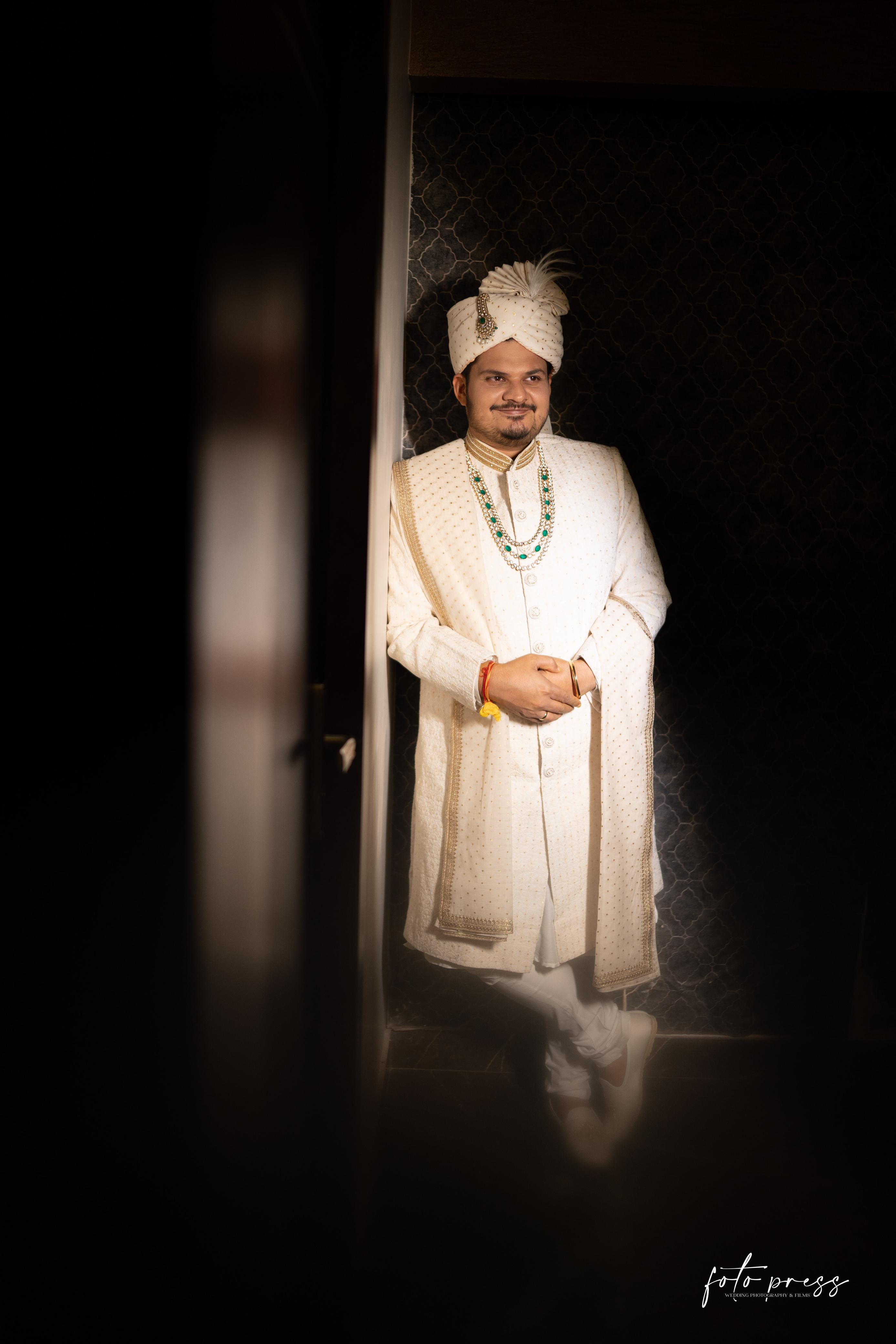Man in traditional white attire with a turban standing in a doorway.